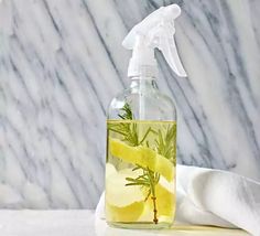 a hand sanitizer with lemon slices and rosemary in it on a marble surface