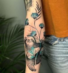 a person with a tattoo on their arm holding a raccoon and flower branch