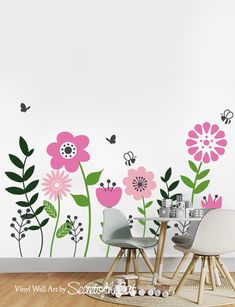 a wall with flowers and butterflies painted on it in the corner, next to two chairs