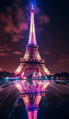 the eiffel tower lit up at night with its reflection in the water below