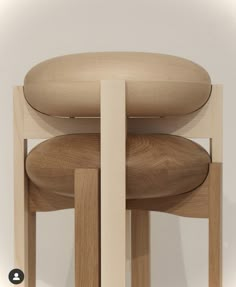 a wooden chair sitting on top of a white floor next to a table with an oval shaped cushion