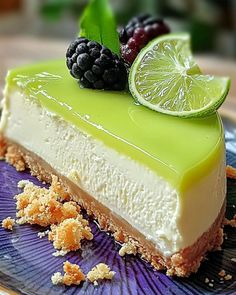 a piece of cheesecake with lime and blackberries on top is sitting on a plate