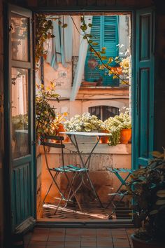 Cozy small balcony design featuring potted plants, a metal table and chairs, and warm lighting, set against vintage blue shutters. A Modern House, Photo Room, Craft Photography, Bohemian Minimalist