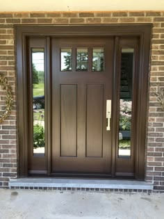 a brown front door with two sidelights and brick pillars on the outside of it