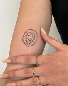 a woman's arm with a small lion tattoo on it