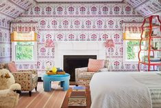 a bedroom with pink and white wallpaper, colorful furniture, and a fire place in the corner