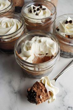 four desserts in small glass bowls on a table