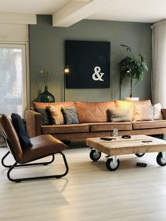 a living room filled with furniture and a large painting on the wall above it's windows