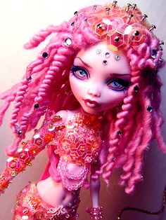 a close up of a doll with pink hair and beads on it's head