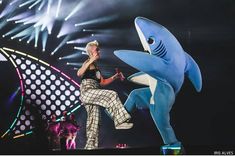 a woman standing on top of a stage next to a shark