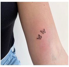 a woman's arm with two small butterflies on the left side of her arm