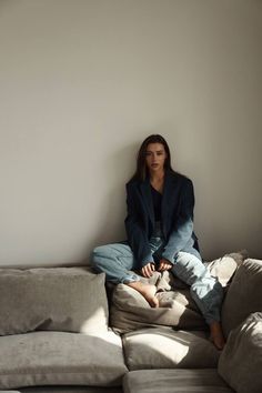 a woman sitting on top of a couch in front of a white wall