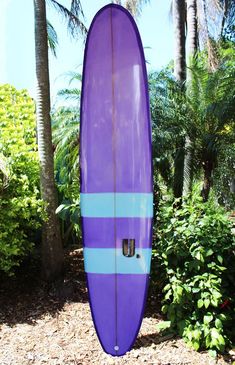 a purple surfboard sitting in the middle of some bushes