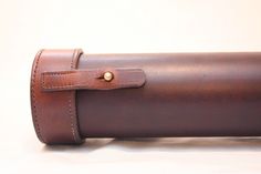 a close up of a brown leather case on a white surface with a gold button