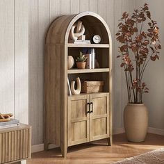 a wooden bookcase with shelves and baskets on it in a room next to a potted plant