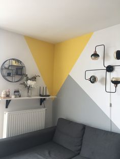 a grey couch sitting in front of a yellow and white wall