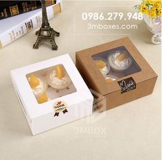 two cupcakes in a box with the eiffel tower in the background