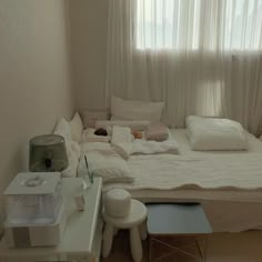 a white bed sitting next to a window in a room with lots of pillows on top of it