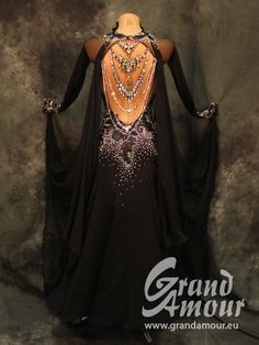 the back of a woman's black dress with beads and chains on her shoulders