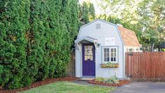 a small white shed sitting next to a wooden fence