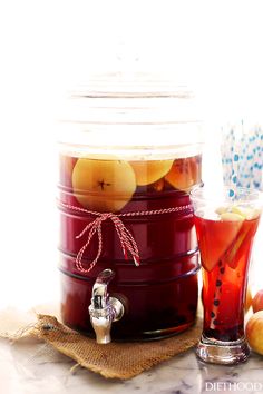 a jar filled with fruit next to a glass full of liquid