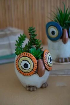 an owl planter sitting on top of a table next to a potted plant