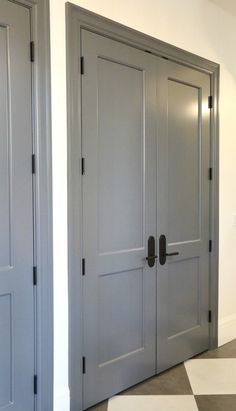 two gray doors in a white room with checkered flooring