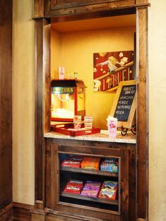 a display case in the corner of a room filled with books and snacks on top of it