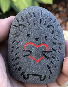 a hand holding a rock with a lion face painted on it's face and the word love written in red