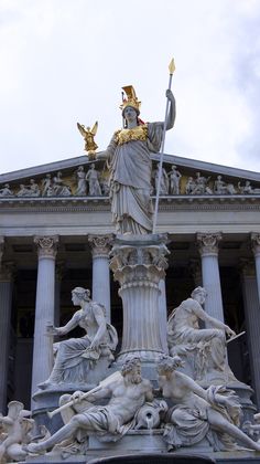 the statue is in front of an old building with columns and statues on it's sides