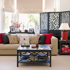 a living room filled with lots of furniture and red pillows on top of it's couches