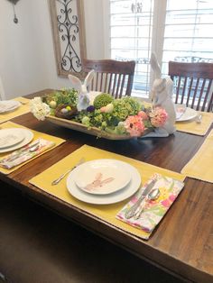 the table is set for easter dinner with bunny decorations and flowers on each placemat