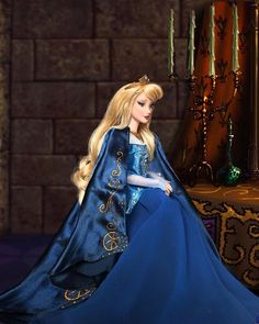 a barbie doll dressed in a blue gown and tiara, sitting on a table