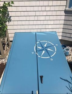 the side of a blue refrigerator sitting in front of a building with a compass on it