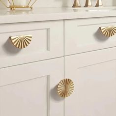 a white dresser with gold handles and knobs on the drawers in front of it