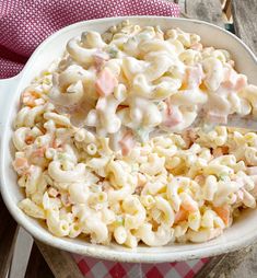 a white bowl filled with macaroni and cheese on top of a checkered table cloth