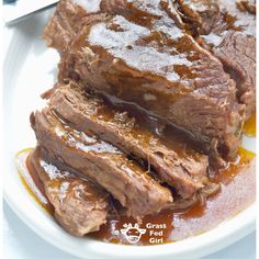 a white plate topped with meat covered in gravy and sauce next to a fork