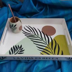 a tray with a painting on it and a cup in the middle next to it