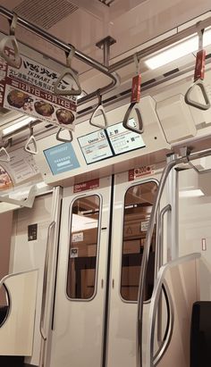 the inside of a subway car with doors and signs hanging from it's ceiling