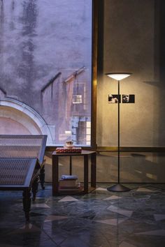 two benches sitting in front of a window next to a table with a lamp on it