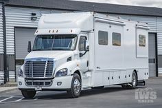 a white truck is parked in front of a building with garage doors on the side