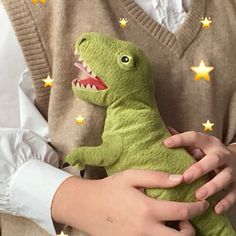 a person holding a green stuffed animal with stars on it's sleeves and chest