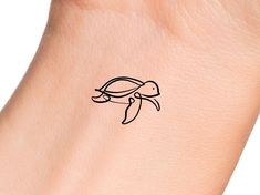 a small tattoo on the wrist of a woman's arm, depicting a turtle