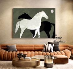 a living room with a couch, coffee table and horse painting on the wall above it