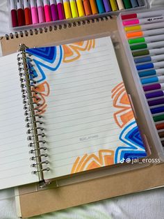 an open spiral notebook with colored pencils next to it