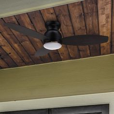 a ceiling fan mounted to the side of a wooden wall next to a black door