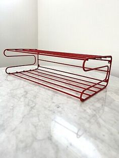 a red metal shelf sitting on top of a marble counter