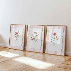 three framed pictures on the wall in an empty room with wood flooring and white walls