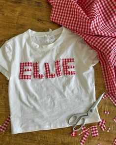 a red and white gingham shirt with the word ellene on it next to scissors