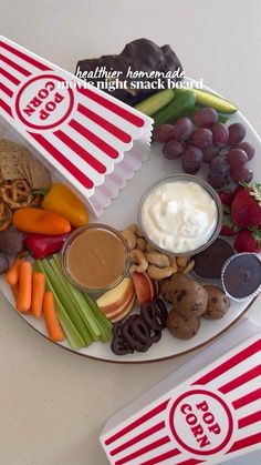 a plate filled with fruit, vegetables and crackers next to a cup of yogurt